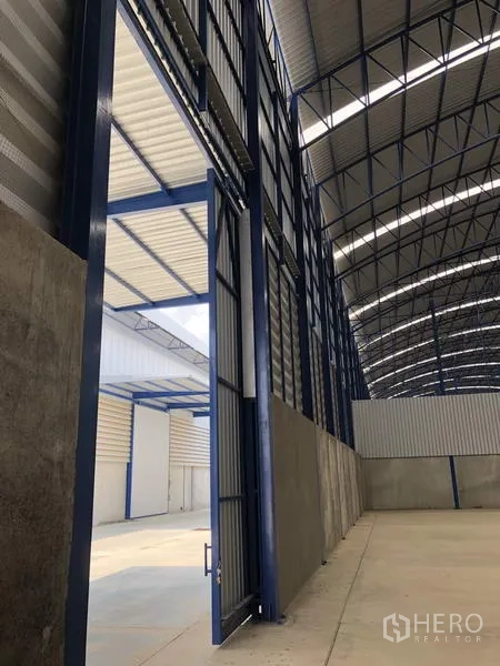 工厂 出租在Lat Lum Kaeo, Pathum Thani - 高挑工业推拉门与钢结构，通向室外装卸区域。