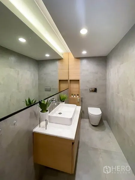 Townhouse for rent in Khlong Toei, Bangkok - Sleek powder room with floating vanity and an expansive mirror.