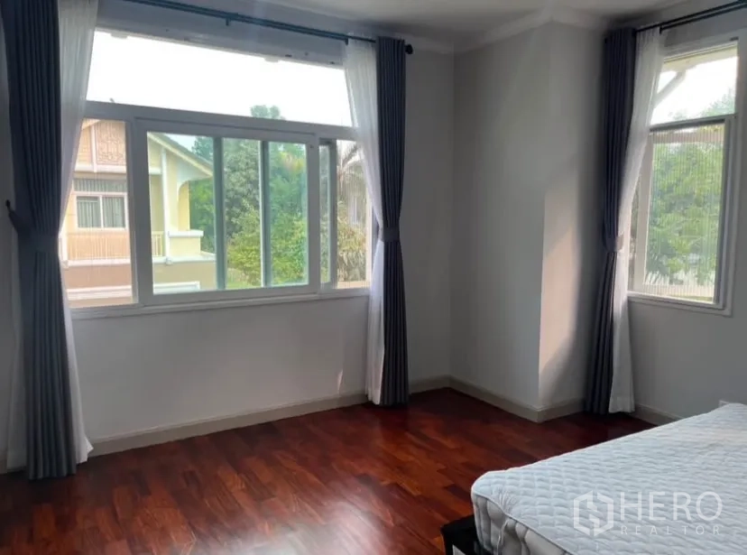 独立式住宅 出租或出售在Lat Phrao, Bangkok - 主卧大转角窗，花园景观与窗帘。