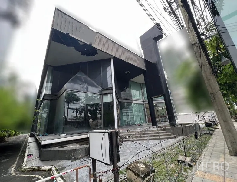 Retail Space for rent - Modern corner retail building exterior with angular glass facade and wide entry steps.