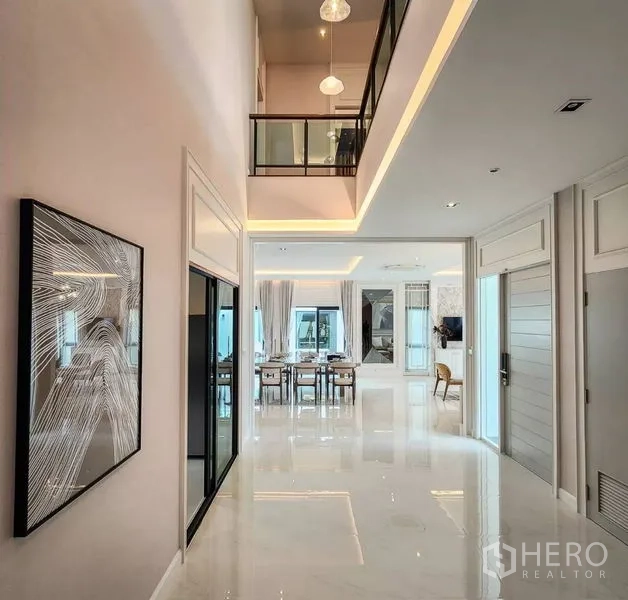 Detached House for sale in Bang Phli, Samut Prakan - Double-height foyer with glossy floors and glass balustrade overlooking living area.