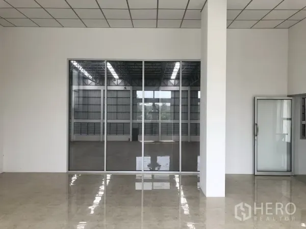 Factory for rent in Phra Nakhon Si Ayutthaya - Glass-partitioned office overlooking the production floor with polished tiles.
