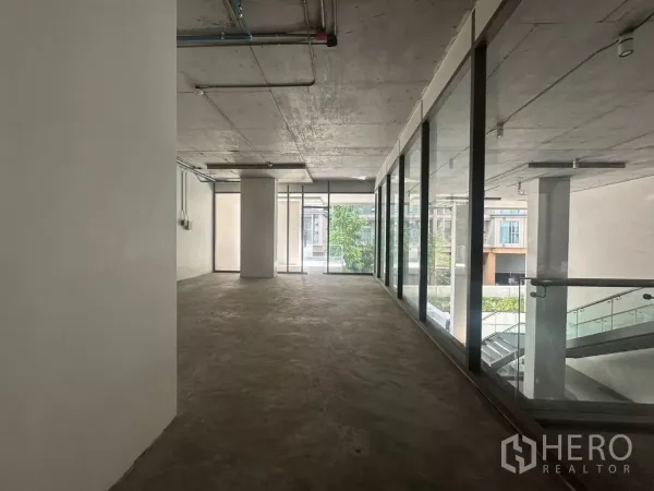 Retail Space for rent - Long rectangular shop space with glass wall to the corridor and views of greenery.