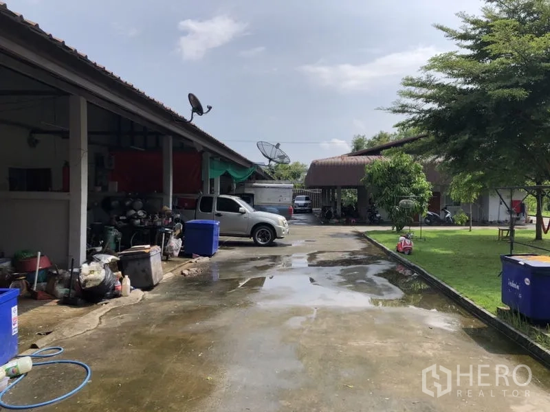 Detached House for sale in Lam Luk Ka, Pathum Thani - Side view of service buildings, parking areas and green lawn.
