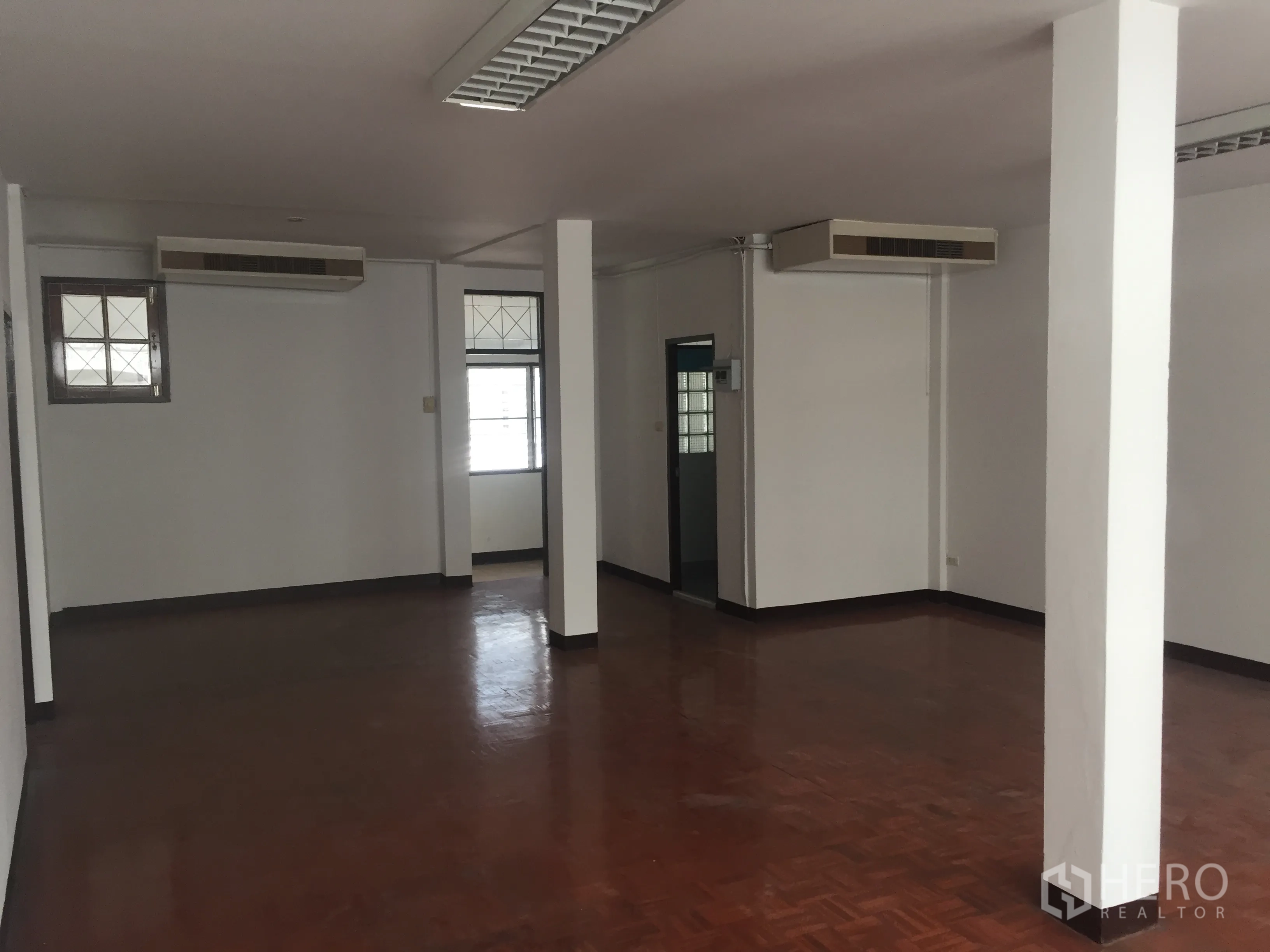 Home Office for rent in Watthana, Bangkok - Open office room with wood floors, structural columns and ceiling-mounted air-conditioning units.