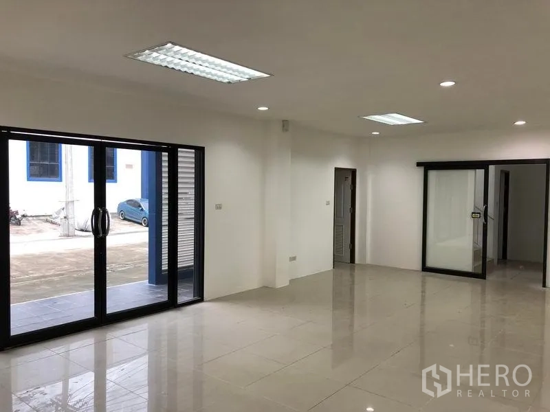 Factory for rent or sale in Samut Prakan - Bright office area with glass partitions opening to the driveway and yard.