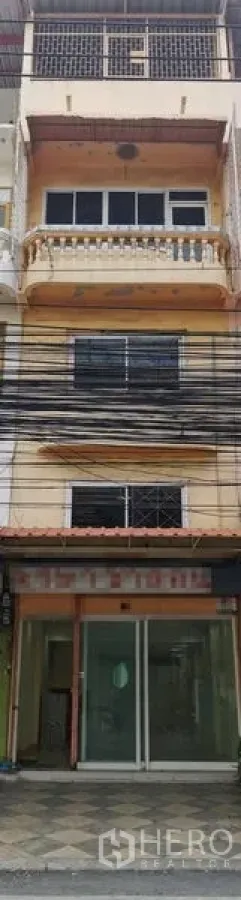 Shophouse for rent in Suan Luang, Bangkok - Four-storey shophouse facade with sliding glass storefront and balconies.