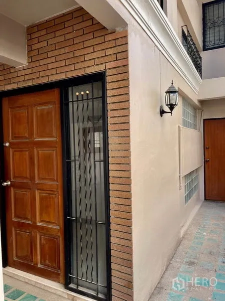 Home Office for rent in Khlong Toei, Bangkok - Main entrance showing wooden door, exterior lantern and brick wall detail.