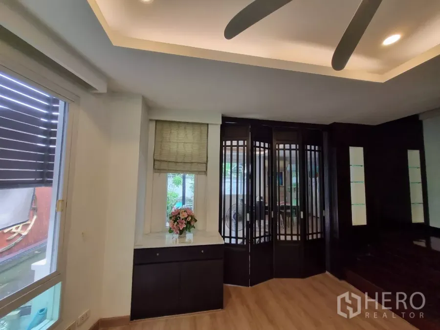 Detached House for rent in Bang Kapi, Bangkok - Modern living area with ceiling fan, wood floors, and folding glass partition.