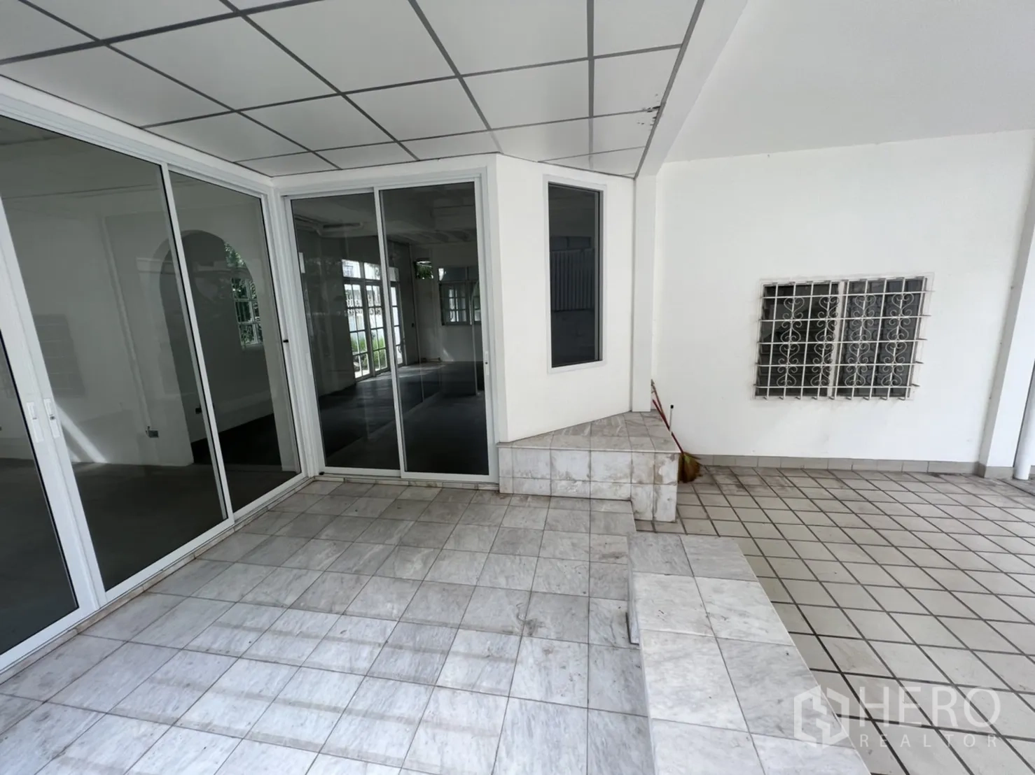 Detached House for rent or sale in Sathon, Bangkok - Covered tiled terrace with large sliding glass walls and built-in steps.