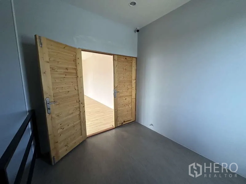 Factory for rent or sale in Lam Luk Ka, Pathum Thani - Double wooden doors opening to an office with light wood floors.