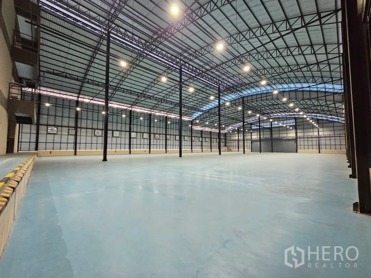 Factory for rent in Si Racha, Chon Buri - Large clear-height warehouse area with distant roller door access and smooth floor.