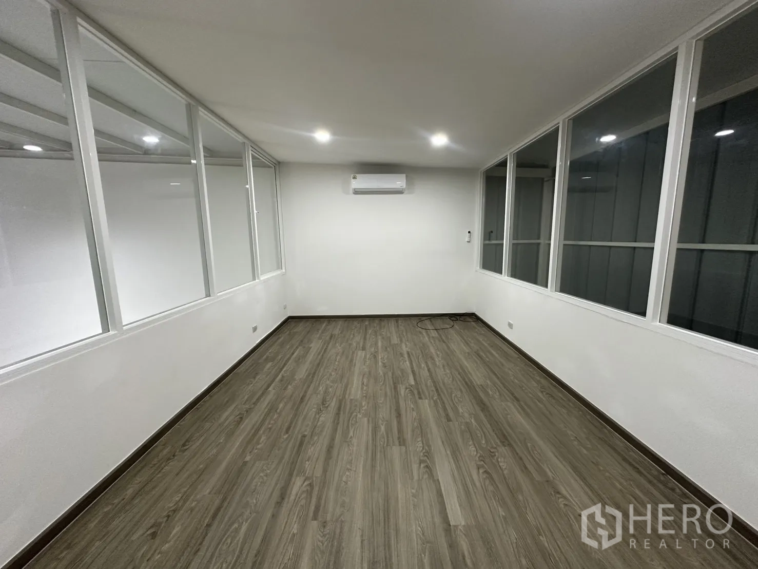 Warehouse for rent in Suan Luang, Bangkok - Bright mezzanine office with wood‑look flooring, white walls, glass partitions and a wall‑mounted air conditioner.