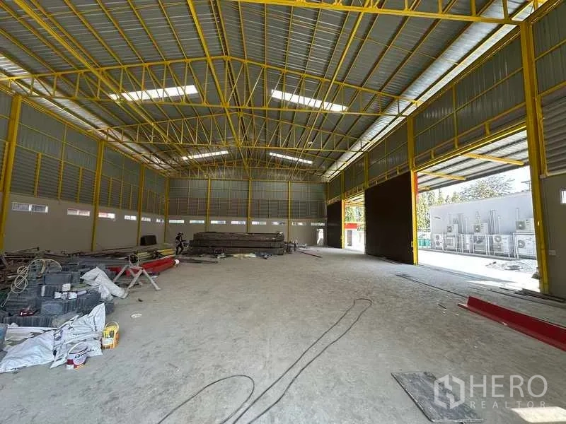 Warehouse for rent in Lam Luk Ka, Pathum Thani - Interior of the warehouse featuring high clear-span steel trusses, ventilated walls, and an open floor for storage or operations.