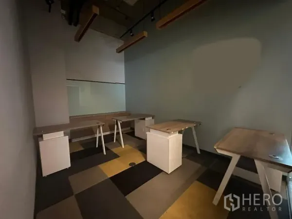 Office Space for rent - Workroom with built-in desks, track lights and a glass partition.