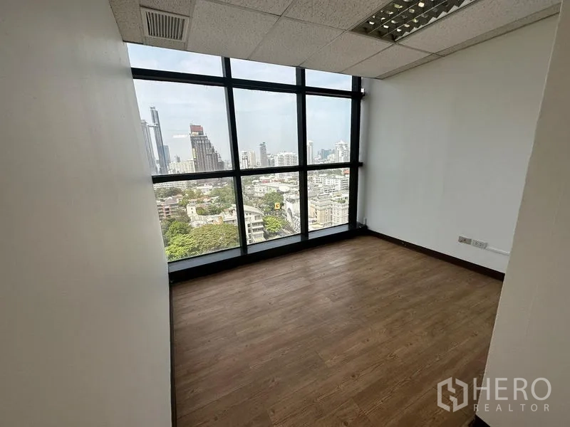 Office Space for rent - Private office with panoramic city view through large black-framed windows and wood flooring.