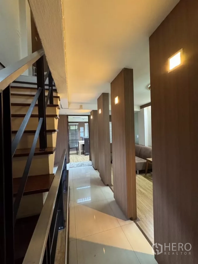 Shophouse for rent in Bang Rak, Bangkok - Long corridor with stairs and illuminated wood pillars leading to living spaces.