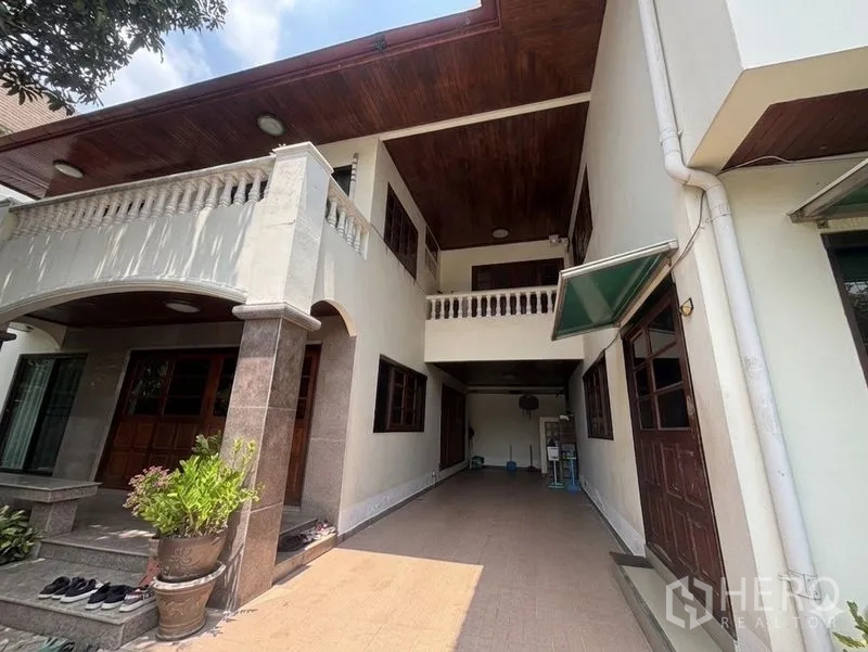 Detached House for sale in Suan Luang, Bangkok - Exterior side view with covered carport, arches and balcony railings.