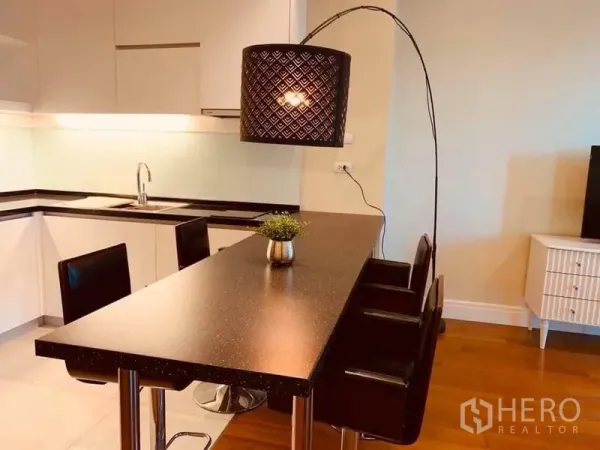 Condominium for rent in Khlong Toei, Bangkok - Close view of the kitchen island and patterned pendant lamp with a sleek black countertop.