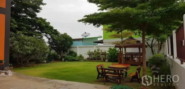 Factory for sale in Bang Phli, Samut Prakan - Landscaped garden yard with green lawn, trees, wooden gazebo and outdoor seating beside the factory.