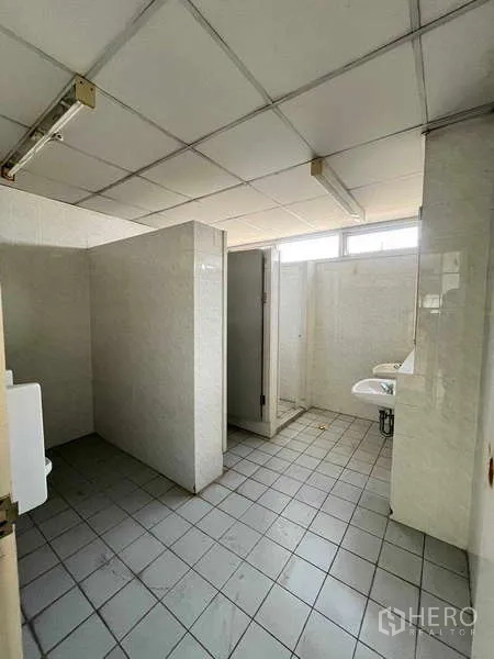 Warehouse for rent in Lat Krabang, Bangkok - Restroom with stalls, sinks and tiled walls inside the warehouse facility.