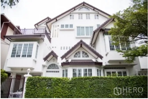 独立式住宅 出租在Khlong Toei, Bangkok - 白色多层独栋别墅正立面，山墙屋顶、凸窗与高绿篱。