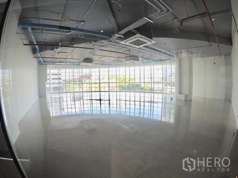 Retail Space for rent in Khlong Toei, Bangkok - Spacious unit with full-height glazing, reflective flooring, and an industrial-style exposed ceiling.