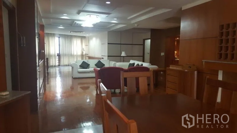 Condominium for rent in Khlong Toei, Bangkok - View from dining table toward long living area with ceiling lights and a bar counter.