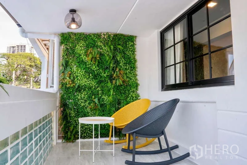 Townhouse for rent in Khlong Toei, Bangkok - Balcony lounge with vertical garden wall, two rocking chairs and a small round table.