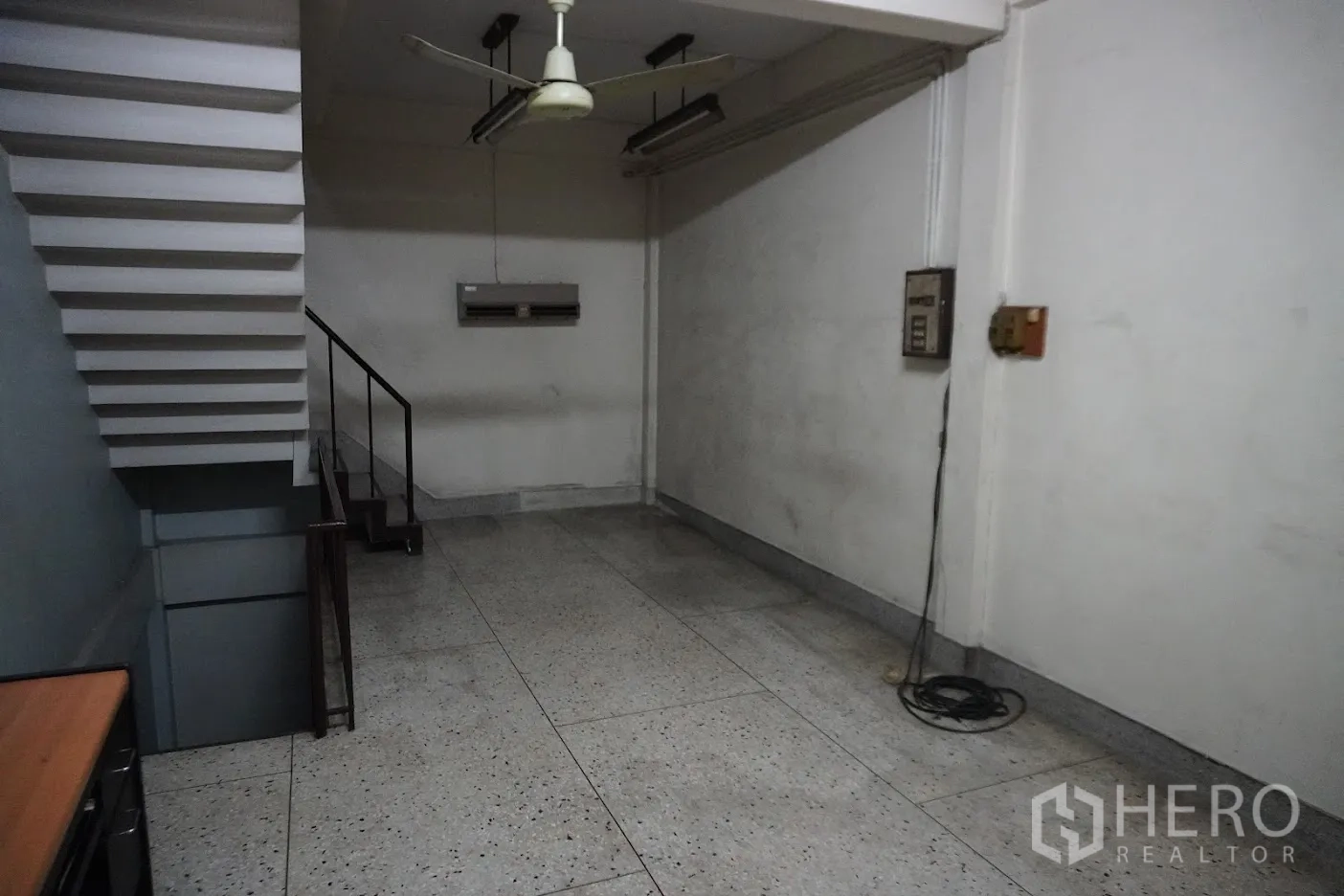 店屋 出租在Watthana, Bangkok - 楼梯下的长形房间，吊扇与水磨石地面。