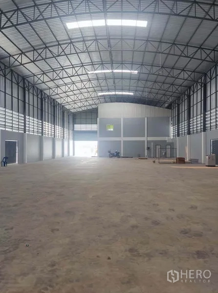 Factory for sale in Mueang Samut Sakhon, Samut Sakhon - Expansive warehouse hall with arched metal roof, mezzanine office and loading doors.