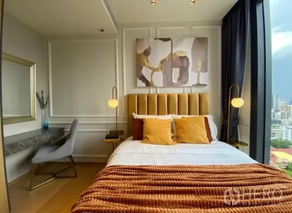 Condominium for rent - Master bedroom with gold headboard, pendant lights and city skyline view through a large window.