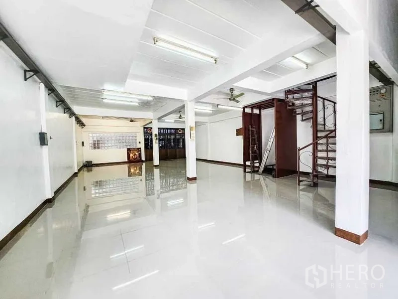 Home Office for rent in Khlong Toei, Bangkok - Open-plan ground floor with spiral stair, utility area and glossy floor tiles.