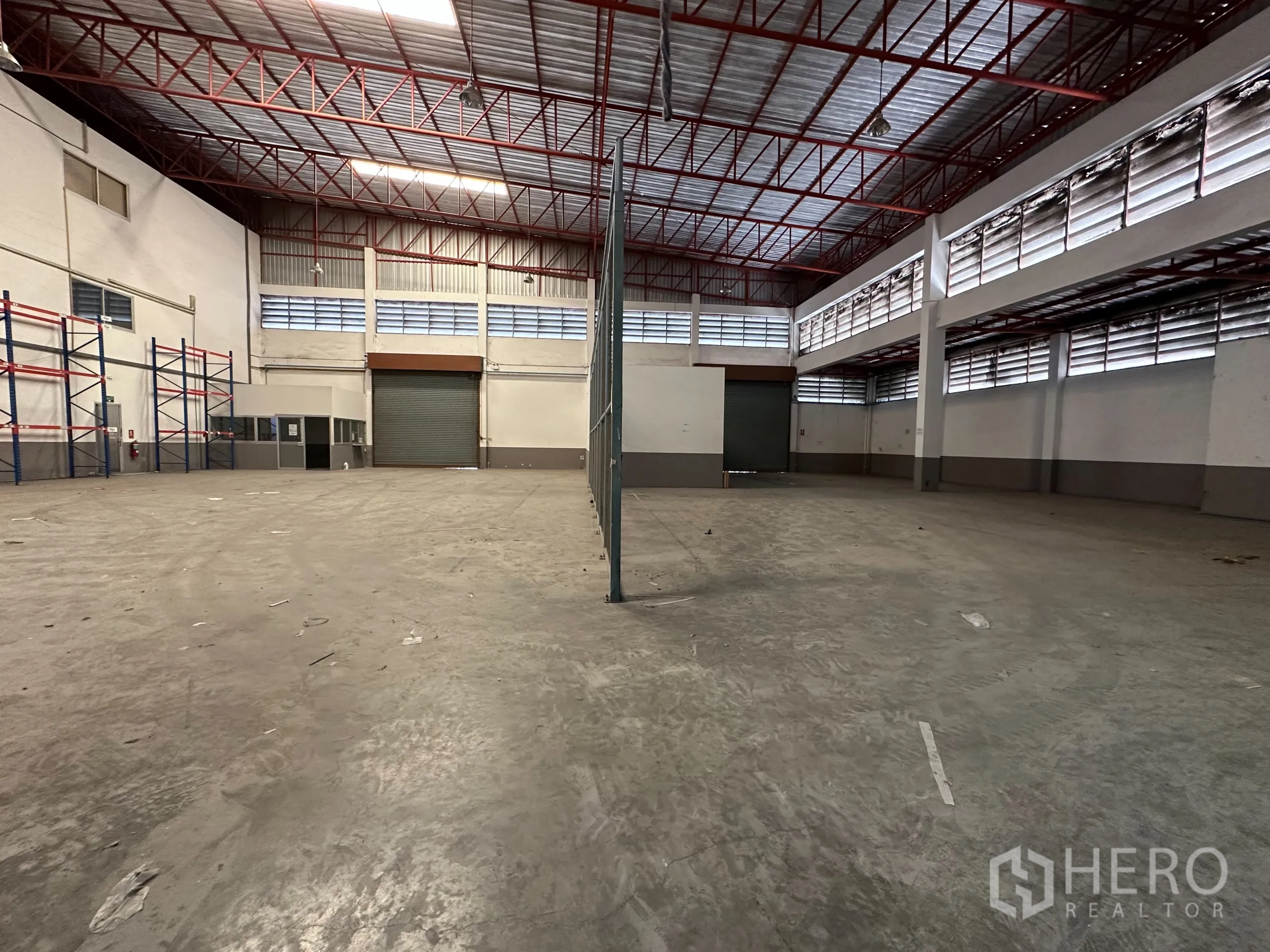 Factory for rent - Spacious warehouse hall with high red truss roof and roller doors.