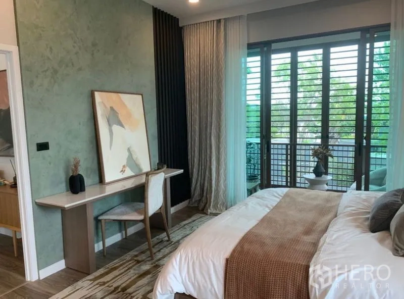 Detached House for sale in Bang Kapi, Bangkok - Primary bedroom with desk, balcony access and full-height louvered windows.