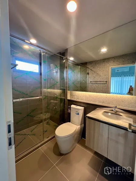 Detached House for rent in Bang Kapi, Bangkok - Bathroom with glass shower, vanity and warm lighting.