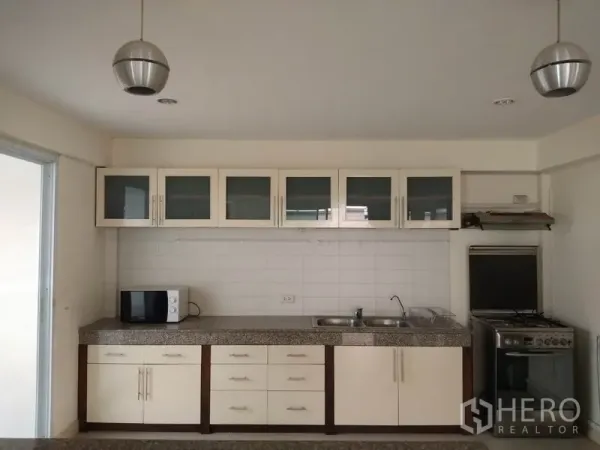 Detached House for rent in Watthana, Bangkok - Bright fitted kitchen with white cabinetry, granite countertops, double sink and gas stove.