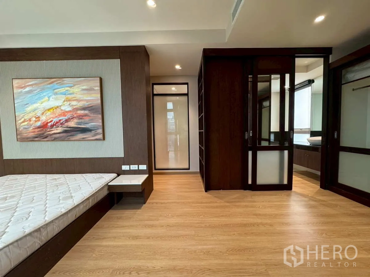 Condominium for rent or sale in Khlong Toei, Bangkok - Master bedroom with dark wood accents, walk-in closet and ensuite access.