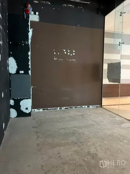 Retail Space for rent in Watthana, Bangkok - Back wall of a vacant retail shop with brown paneling, safety equipment, and a glass entry partition.