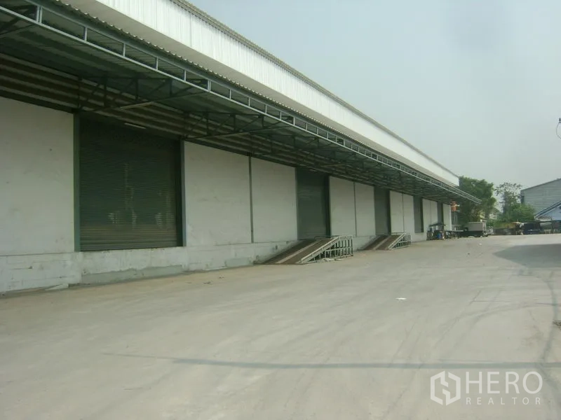 Warehouse for rent in Mueang Samut Sakhon, Samut Sakhon - Long warehouse facade with multiple loading docks and large driveway for trailers.