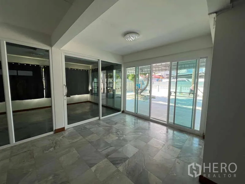 Detached House for rent in Bang Na, Bangkok - Ground-floor sunroom with sliding glass doors and tiled floor facing the yard.