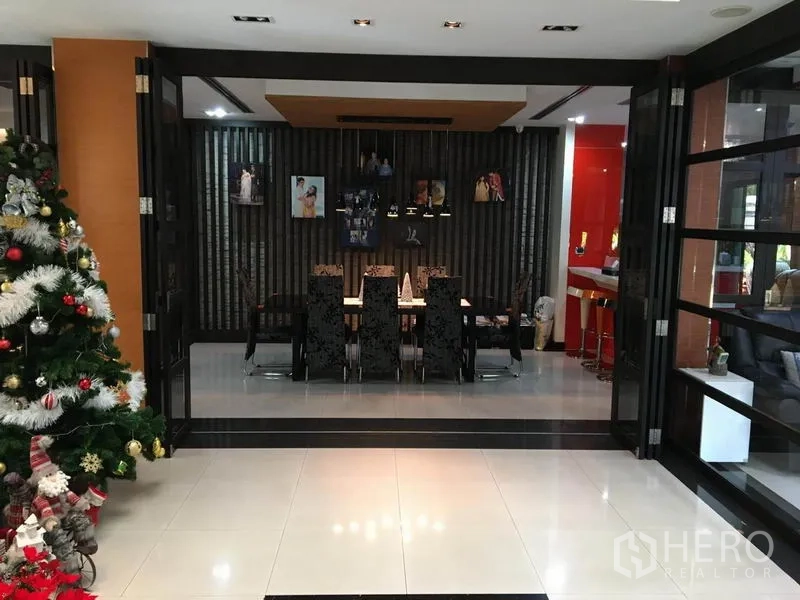 独立式住宅 出租在Khlong Toei, Bangkok - 正式餐厅，长餐桌与软包椅，吊灯照明，折叠玻璃门相连。