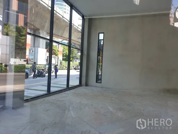 Retail Space for rent in Watthana, Bangkok - Interior view showing tall windows facing Sukhumvit with the elevated BTS track visible outside.