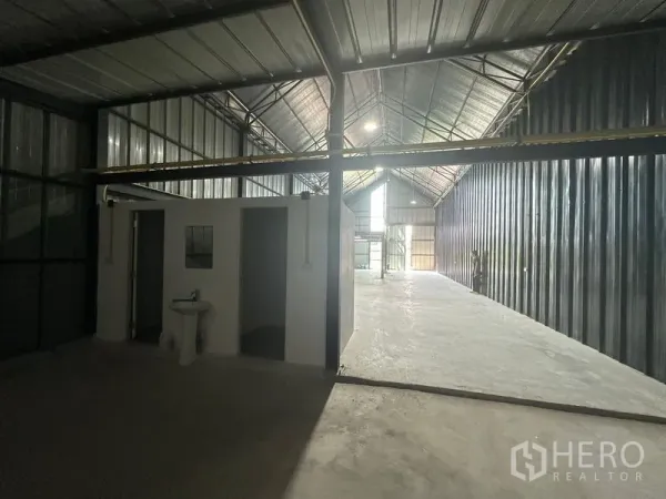 Warehouse for rent in Bueng Kum, Bangkok - Deep warehouse space featuring a built-in restroom block, corrugated metal walls and skylight illumination.