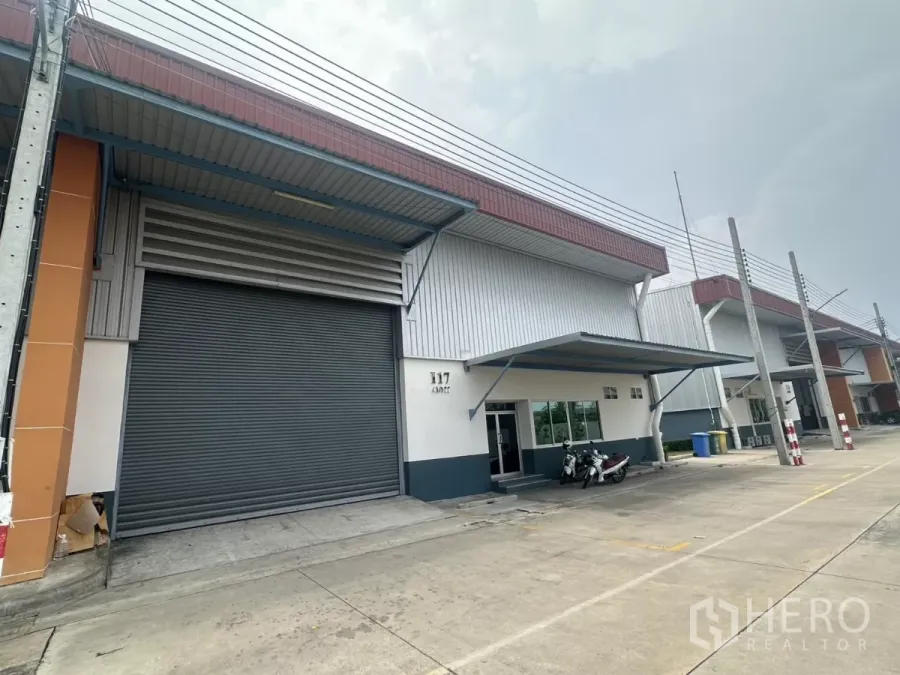 Factory for rent in Bang Phli, Samut Prakan - Modern factory-warehouse exterior in Bang Phli with large roller shutter, covered loading bay and wide driveway.