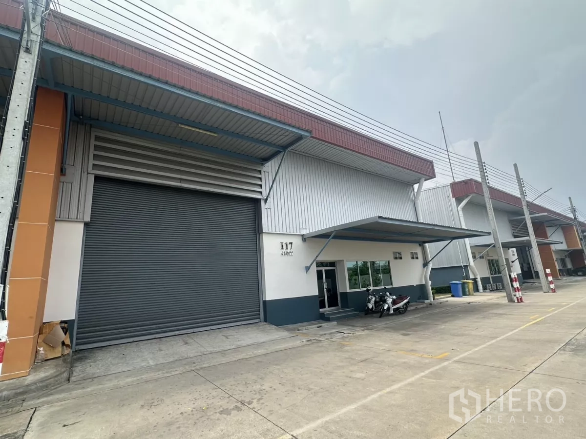 Factory for rent in Bang Phli, Samut Prakan - Modern factory-warehouse exterior in Bang Phli with large roller shutter, covered loading bay and wide driveway.
