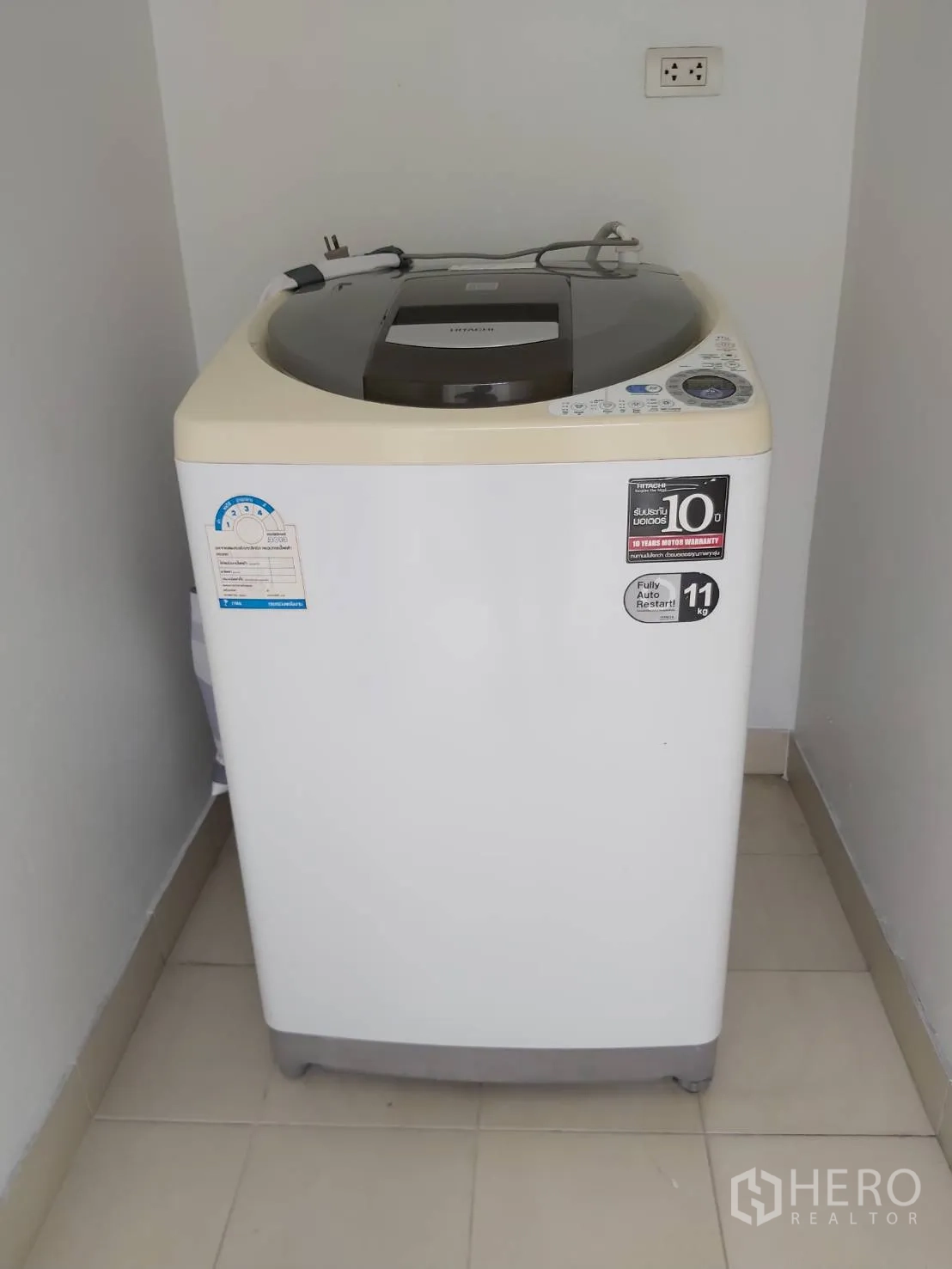 Apartment for rent in Khlong Toei, Bangkok - Top-load washing machine in a separate utility nook with tiled floor and power outlet.