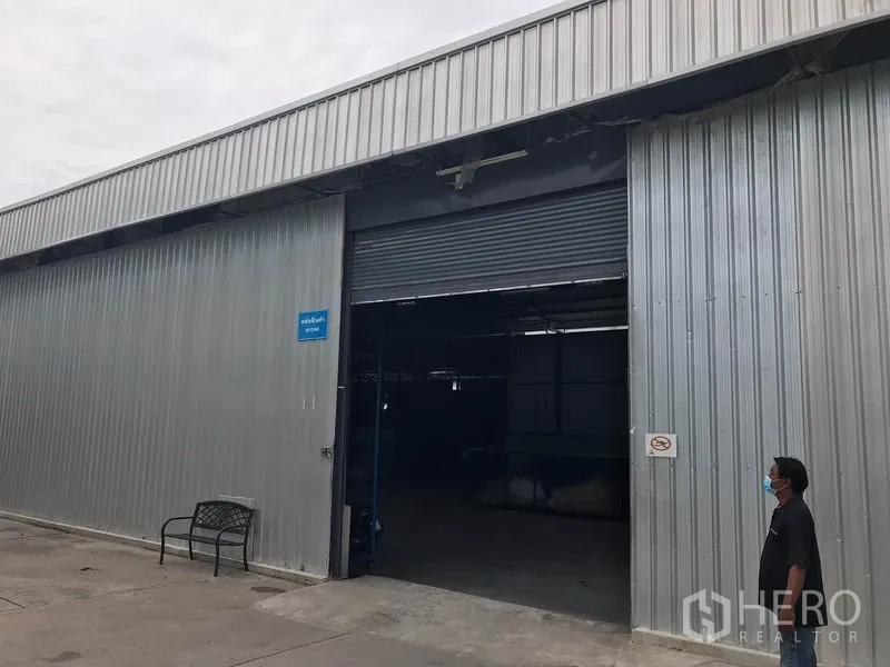 Warehouse for rent in Mueang Chon Buri, Chon Buri - Metal-clad warehouse exterior with a large roller shutter door and wide driveway.