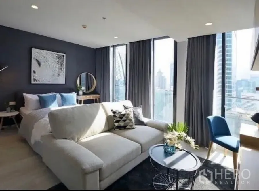 Condominium for rent in Pathum Wan, Bangkok - Another angle of the bright living-bedroom space with sofa, coffee table, and skyline beyond.