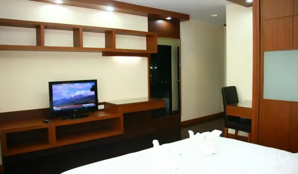 房间 出租在Khlong Toei, Bangkok - 卧室内置木质电视墙与书桌，嵌灯照明